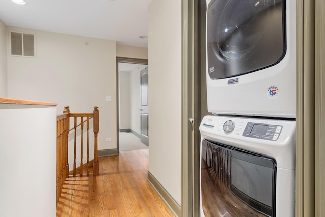 clothes washing area with stacked washer and dryer and light hardwood / wood-style flooring