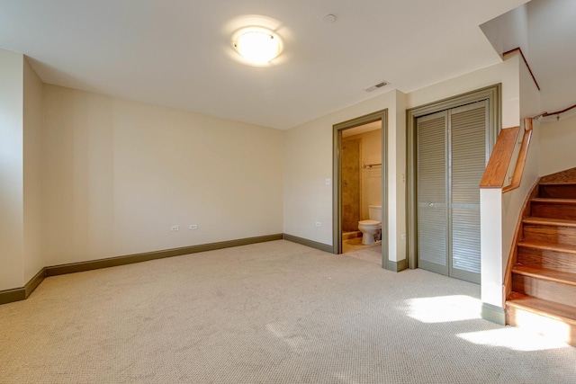 unfurnished bedroom featuring ensuite bathroom, light carpet, and a closet