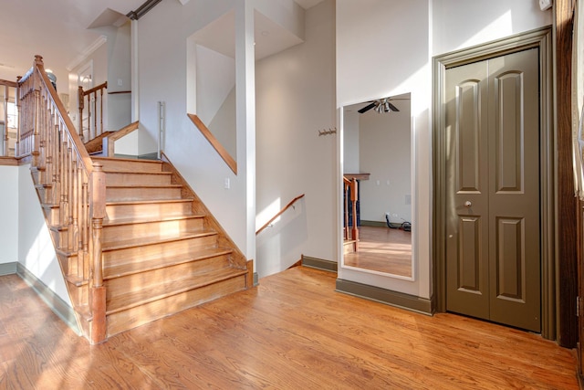 stairs with wood-type flooring and ceiling fan