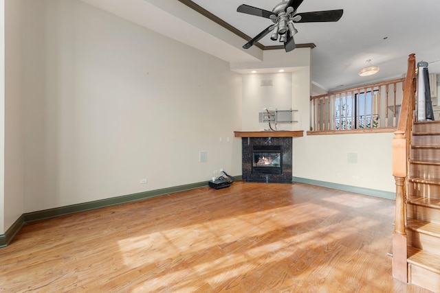 unfurnished living room featuring ornamental molding, wood-type flooring, ceiling fan, and a high end fireplace