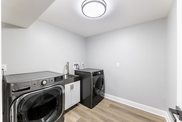 washroom featuring light wood-type flooring, cabinets, sink, and washing machine and clothes dryer