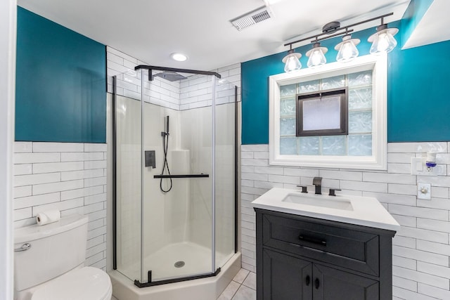 bathroom featuring tile walls, vanity, an enclosed shower, toilet, and tile patterned floors