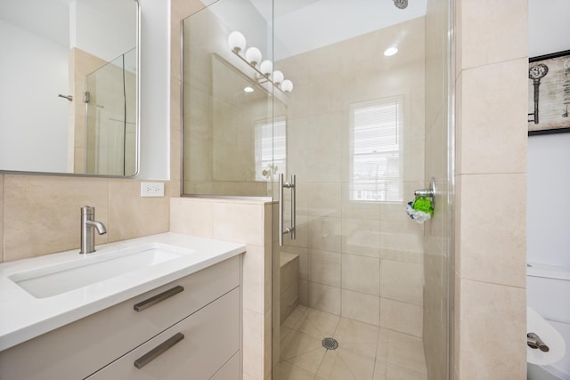 bathroom with tasteful backsplash, vanity, and a shower with door