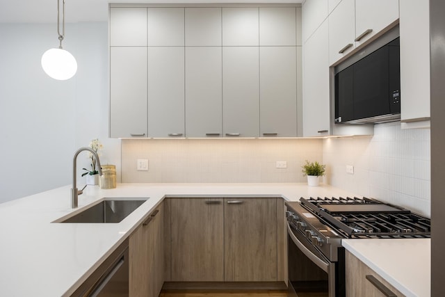 kitchen featuring pendant lighting, sink, gas range, and white cabinets