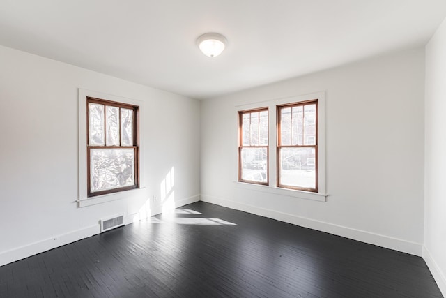 unfurnished room featuring a wealth of natural light and dark hardwood / wood-style floors