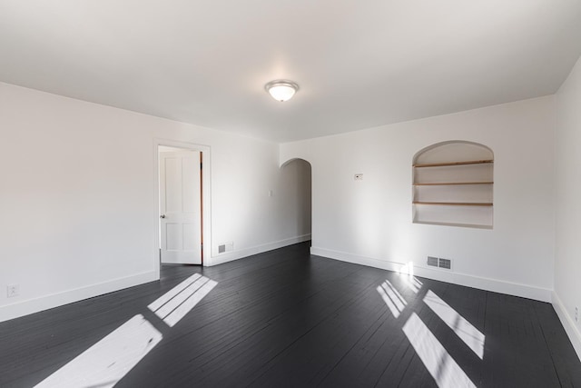 empty room with dark wood-type flooring and built in features