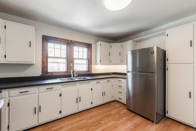 kitchen with white cabinetry, sink, stainless steel fridge, and light wood-type flooring