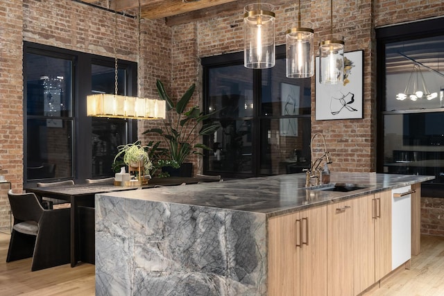 bar with brick wall, sink, light brown cabinets, and light hardwood / wood-style floors