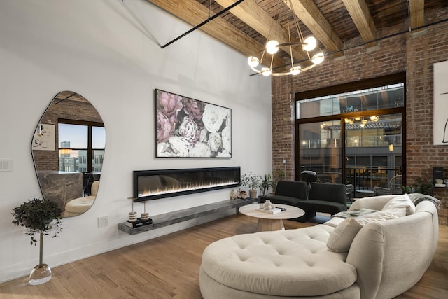 living room featuring wood ceiling, an inviting chandelier, beam ceiling, wood-type flooring, and brick wall