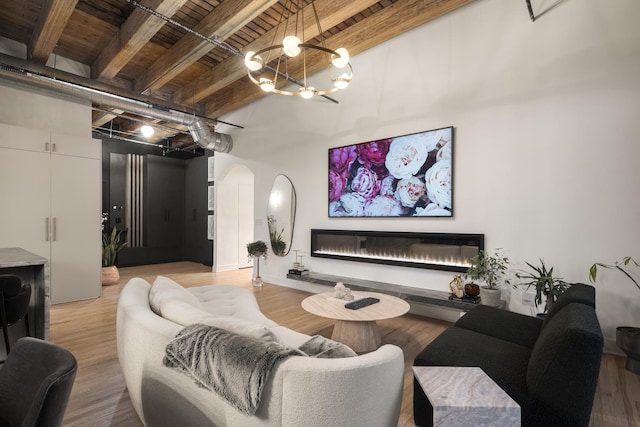 living room featuring wood ceiling, an inviting chandelier, beam ceiling, a high ceiling, and light hardwood / wood-style floors