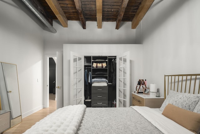 bedroom featuring beam ceiling, light wood-type flooring, and wooden ceiling