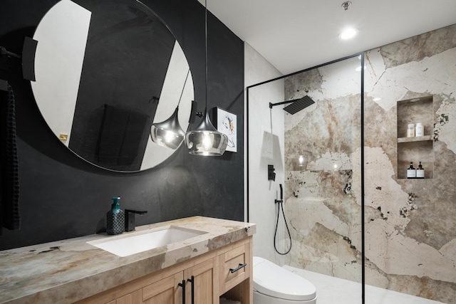 bathroom with vanity, tiled shower, and toilet