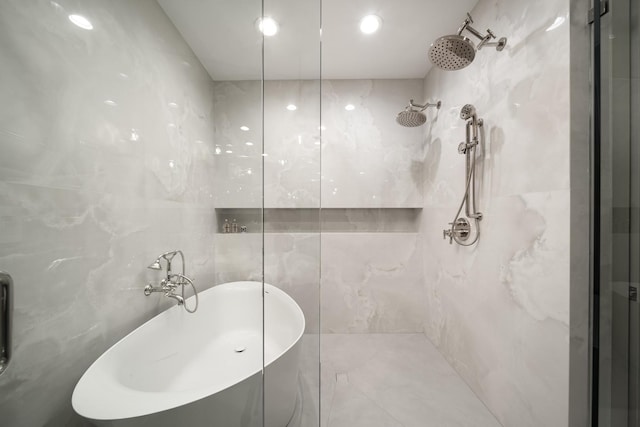 bathroom featuring plus walk in shower, sink, and tile walls