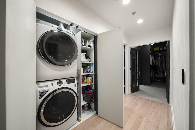 laundry area featuring stacked washer and dryer and light hardwood / wood-style floors