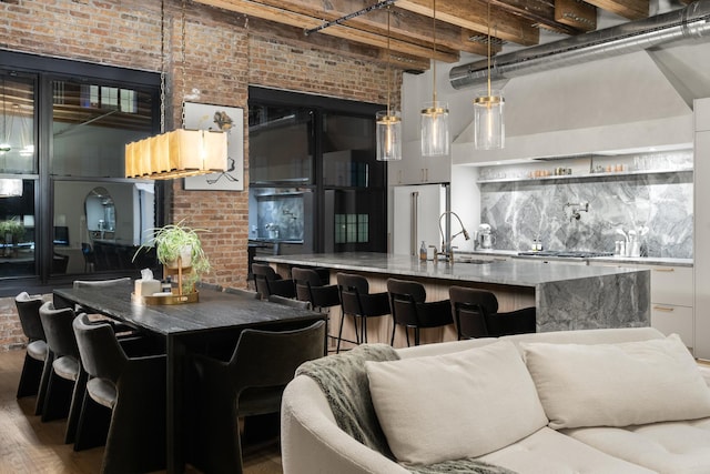 kitchen with brick wall, decorative light fixtures, sink, and wood-type flooring