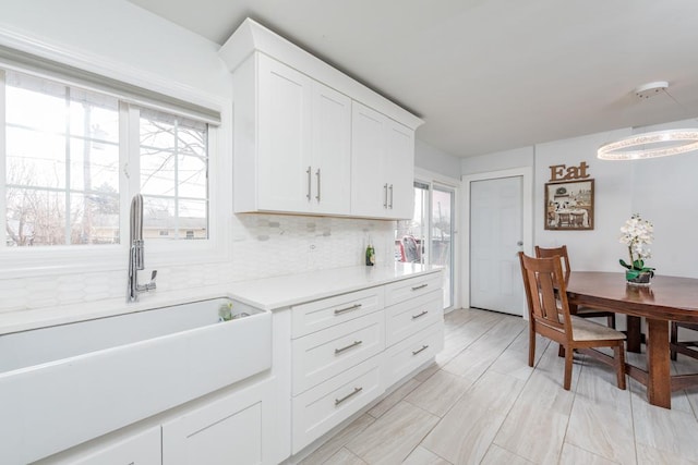 kitchen with tasteful backsplash, white cabinetry, plenty of natural light, and sink