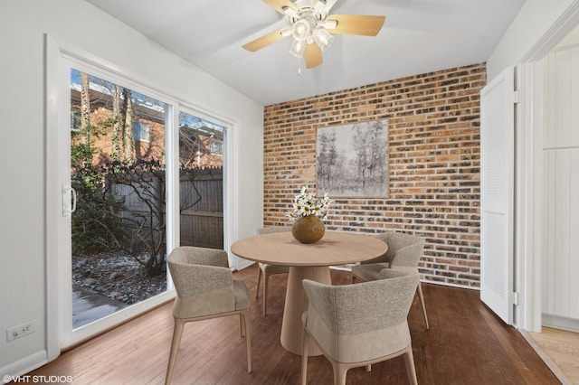 dining area with brick wall and hardwood / wood-style floors