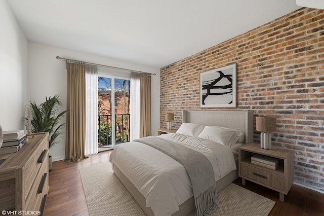 bedroom with brick wall, dark hardwood / wood-style flooring, and access to outside