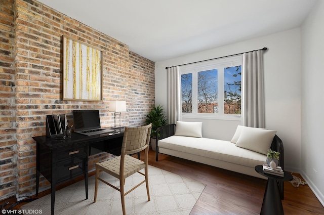 office space with wood-type flooring and brick wall