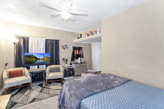 bedroom with ceiling fan, light colored carpet, and a textured ceiling