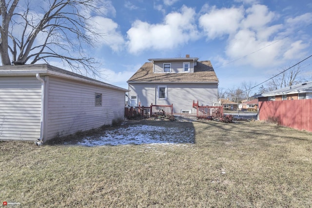 back of property featuring a wooden deck and a lawn