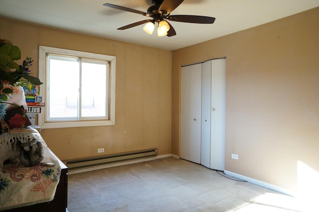 unfurnished room with a baseboard heating unit, light colored carpet, baseboards, and a ceiling fan