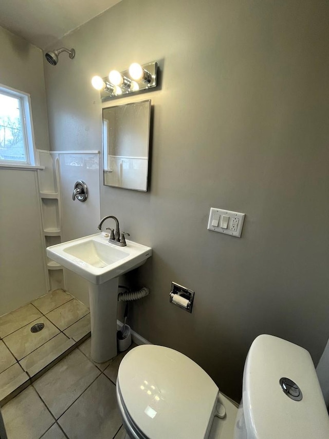 bathroom with walk in shower, sink, tile patterned floors, and toilet