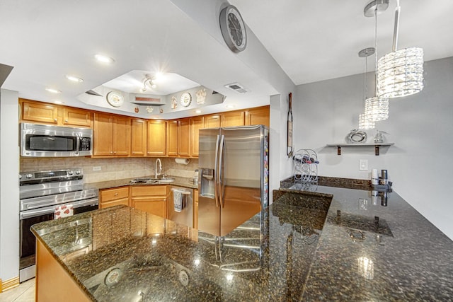 kitchen with appliances with stainless steel finishes, pendant lighting, sink, dark stone countertops, and backsplash