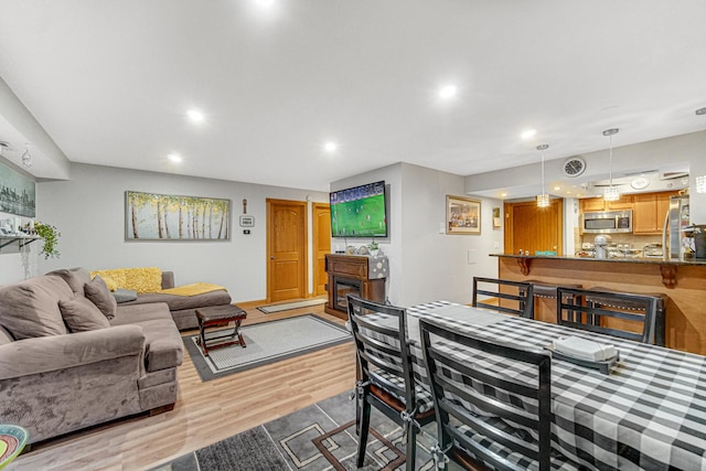 dining space with light hardwood / wood-style floors and indoor bar