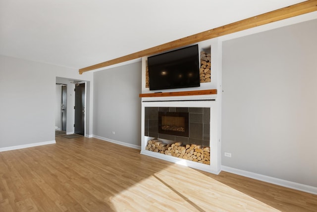 unfurnished living room with hardwood / wood-style flooring, a fireplace, and beam ceiling