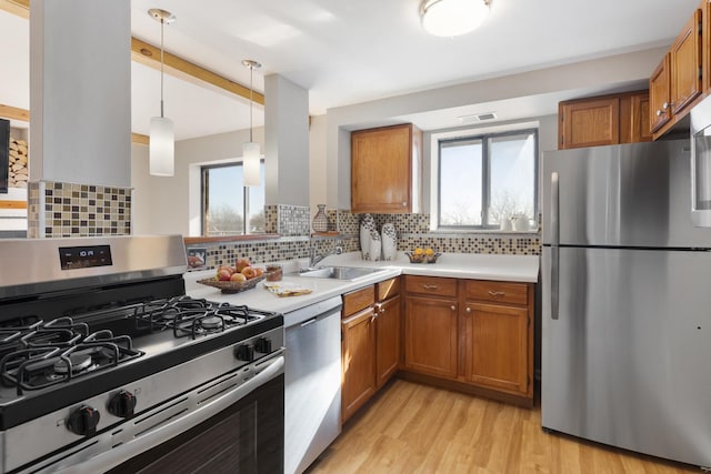 kitchen with stainless steel appliances, sink, decorative backsplash, and decorative light fixtures