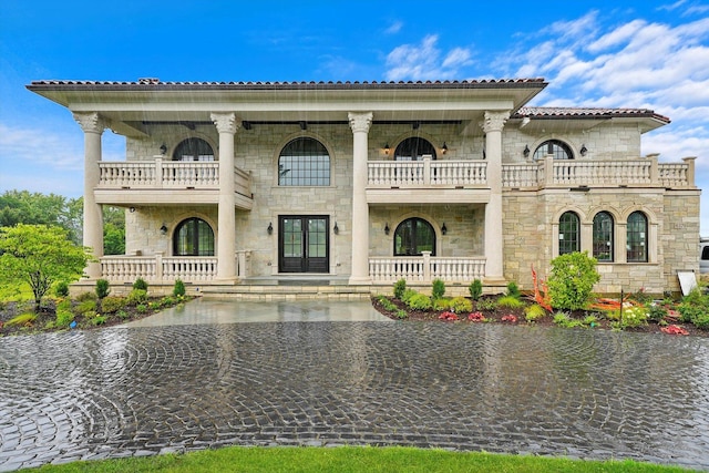 mediterranean / spanish-style house with a water view, a balcony, and french doors