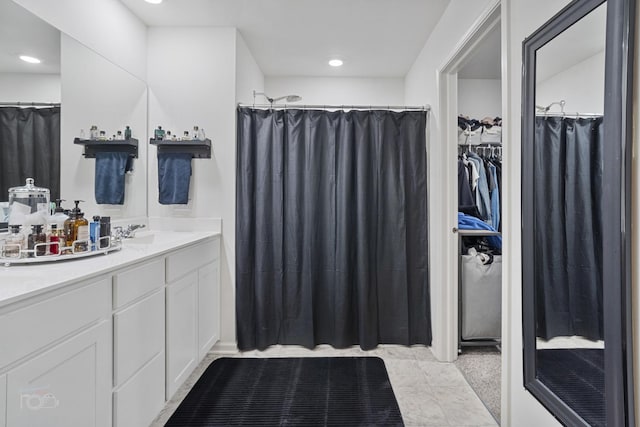 bathroom with recessed lighting, a walk in closet, and vanity