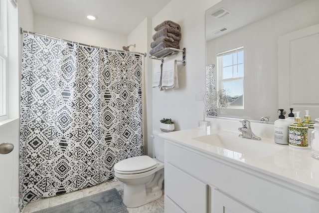 bathroom with toilet, vanity, and visible vents