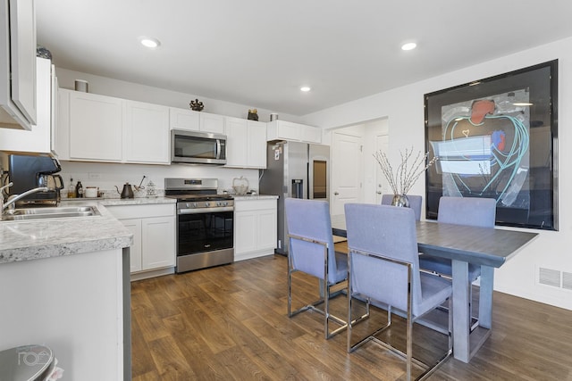 kitchen featuring dark hardwood / wood-style flooring, sink, stainless steel appliances, and white cabinets