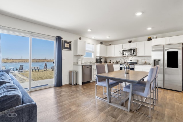 dining space with recessed lighting, a water view, and wood finished floors