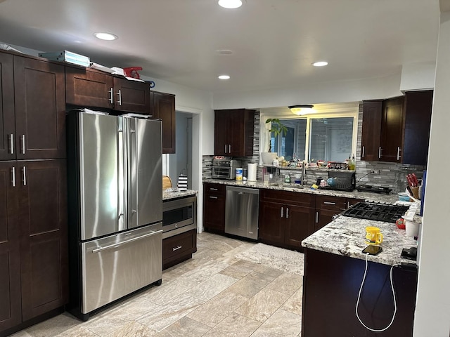 kitchen featuring light stone counters, appliances with stainless steel finishes, sink, and backsplash