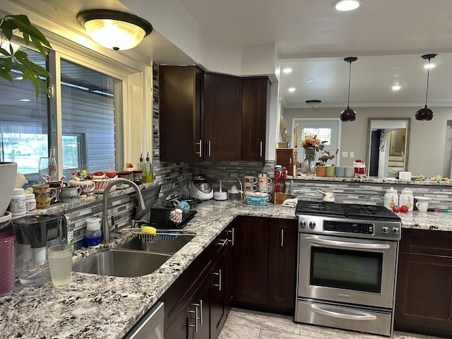 kitchen with sink, stainless steel range with gas stovetop, pendant lighting, light stone countertops, and backsplash