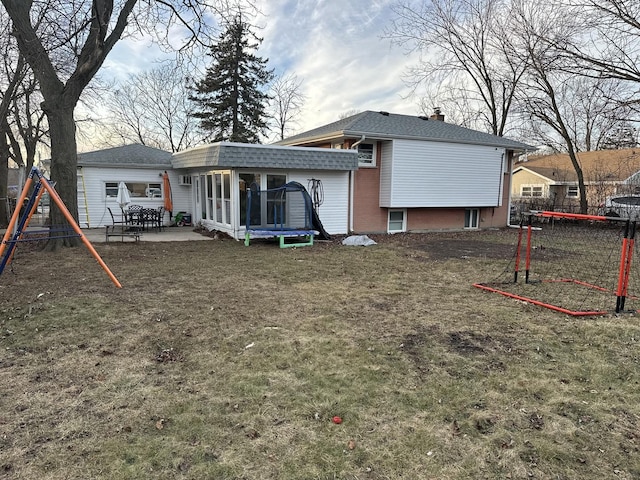 back of property featuring a yard, a playground, a patio area, and a trampoline