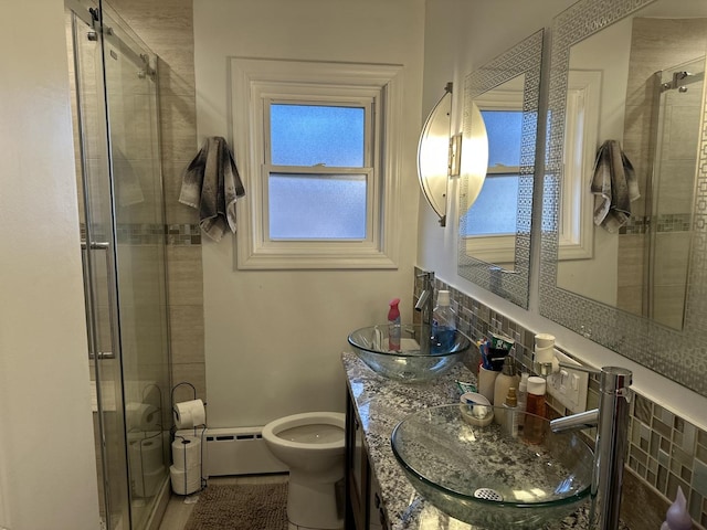 bathroom with a baseboard heating unit, an enclosed shower, vanity, decorative backsplash, and toilet