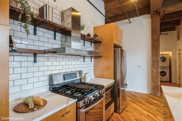 kitchen with appliances with stainless steel finishes, wall chimney range hood, beam ceiling, and decorative backsplash