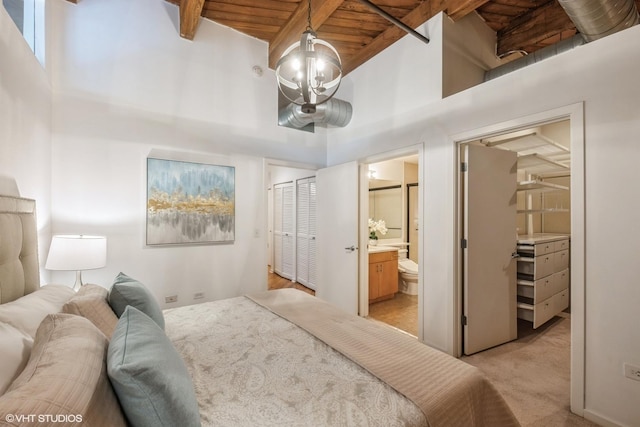 carpeted bedroom with beamed ceiling, ensuite bath, a high ceiling, and wooden ceiling