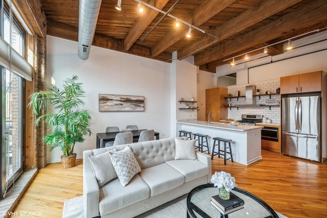 living room featuring light wood-type flooring, sink, wood ceiling, track lighting, and beam ceiling