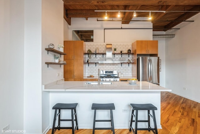 kitchen with a kitchen bar, tasteful backsplash, light hardwood / wood-style flooring, stainless steel fridge, and beam ceiling