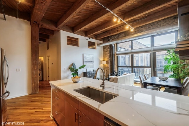 kitchen with sink, wood ceiling, rail lighting, beam ceiling, and light wood-type flooring