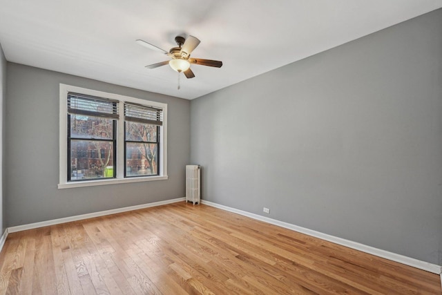 unfurnished room with ceiling fan, radiator heating unit, and light wood-type flooring