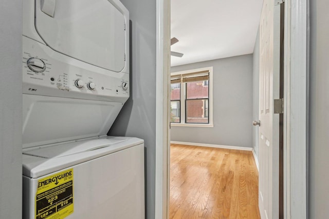 laundry room with stacked washing maching and dryer and light hardwood / wood-style floors