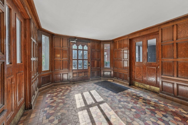 foyer with crown molding and wood walls