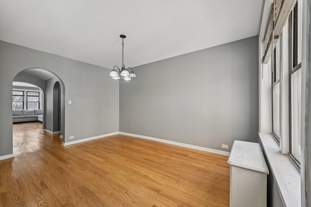 spare room with an inviting chandelier and light wood-type flooring