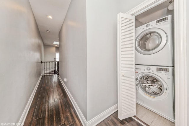 clothes washing area featuring stacked washer and clothes dryer and dark wood-type flooring